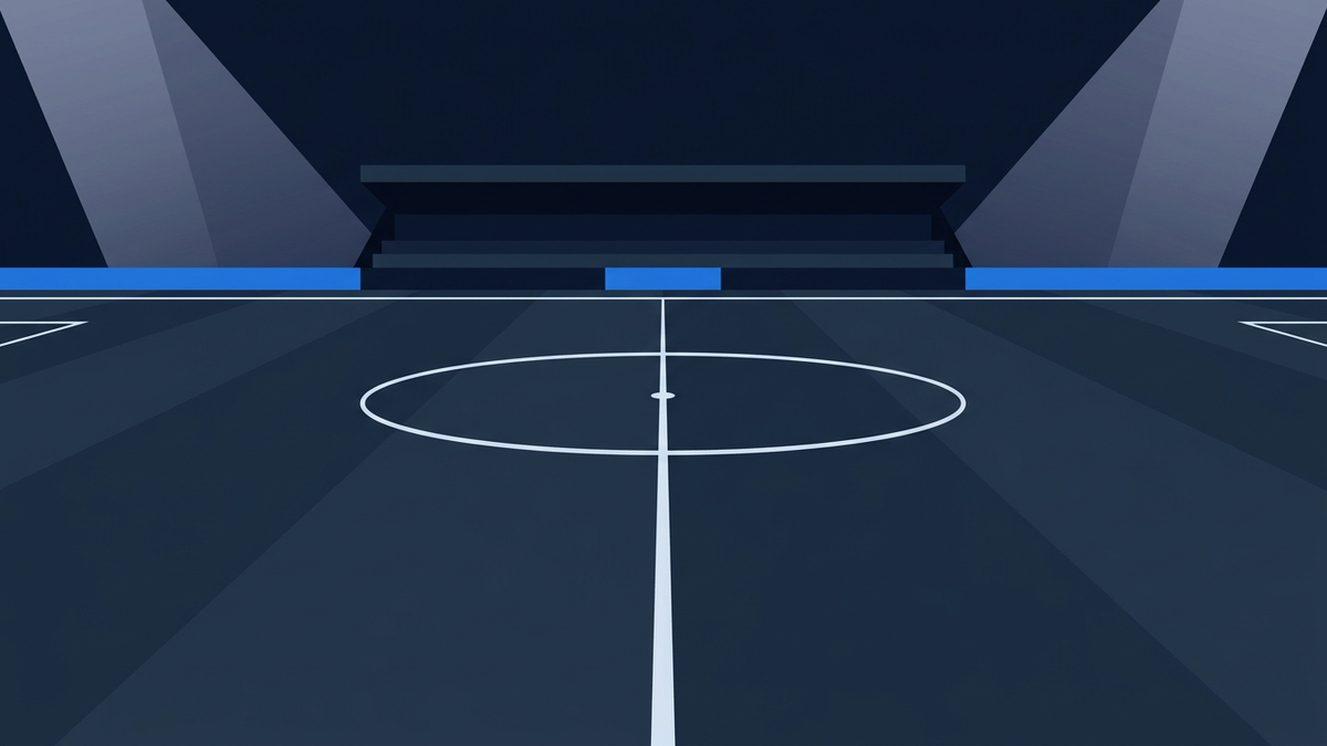 An empty football pitch at night in deep navy, seen from pitch level at the halfway line, the white halfway line running away to a far touchline with the centre circle and centre spot in the foreground, blank blue hoardings in front of an empty dark stand, and pale light shafts from floodlights outside the frame