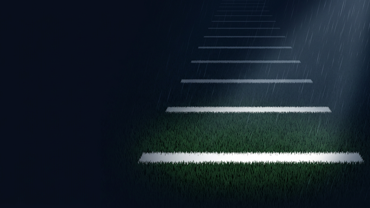 A rain-soaked American football field at night, lit by a spotlight revealing white yard lines on dark green grass, with rain streaks falling diagonally across a deep navy background.
