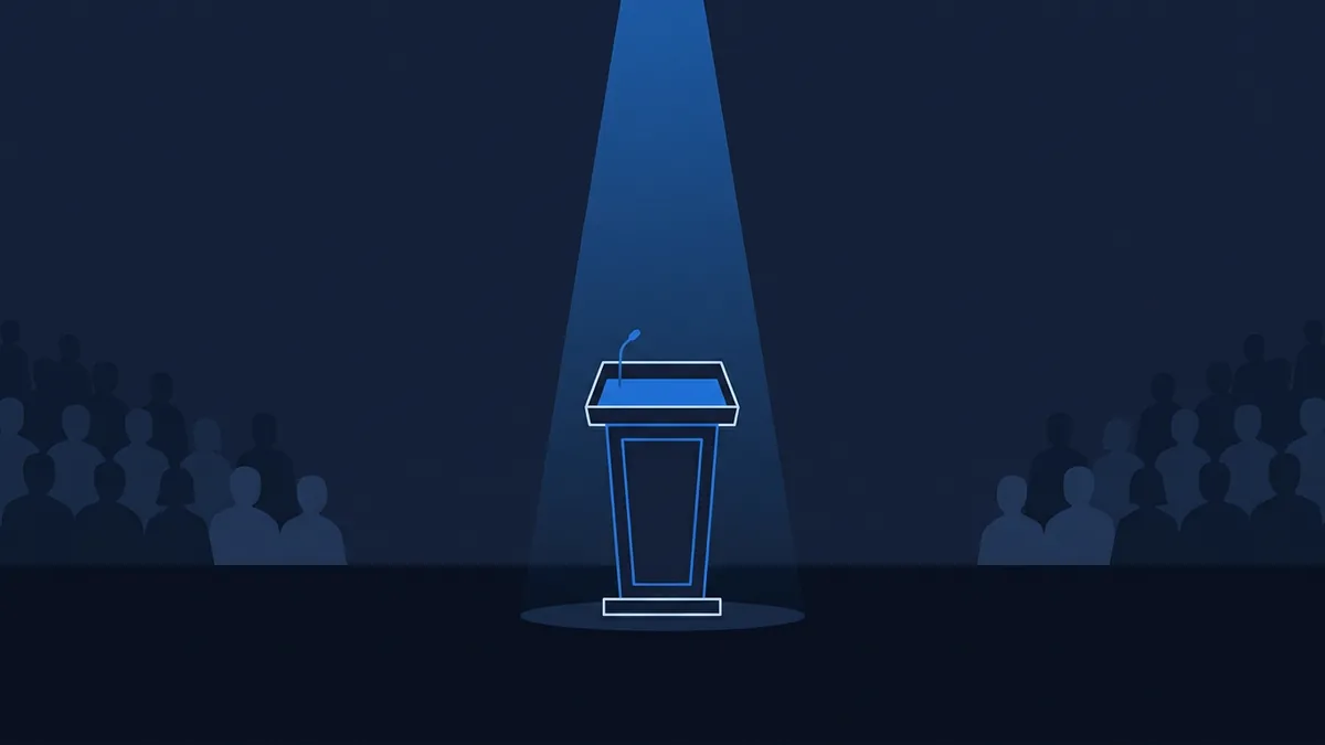 An empty podium with a microphone stands centre stage under a bright blue spotlight, surrounded by silhouetted audience figures on both sides against a deep navy background.